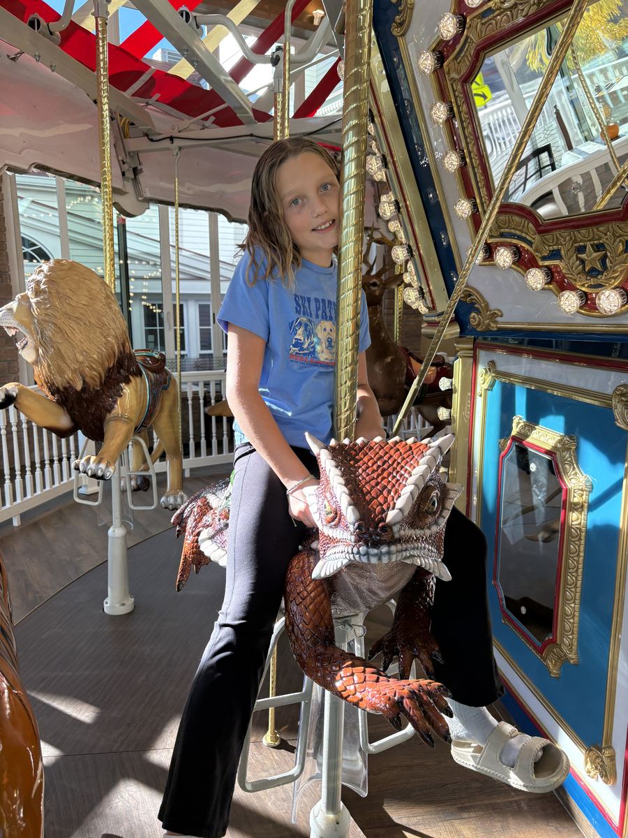 Rebekah riding a dragon on the carousel